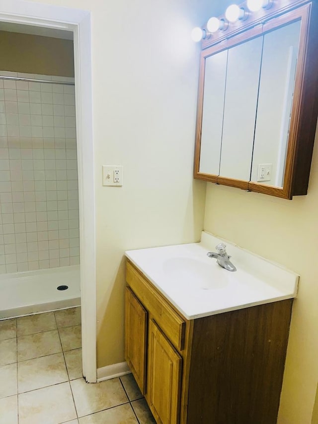 full bath featuring tile patterned floors, baseboards, a stall shower, and vanity