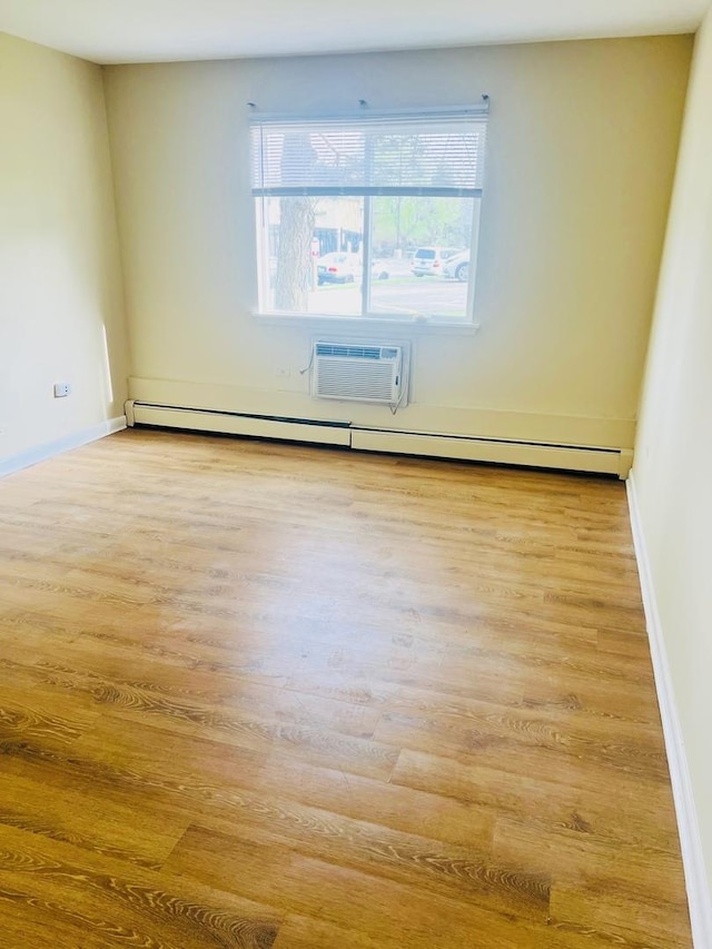 unfurnished room featuring an AC wall unit, light wood finished floors, and baseboards