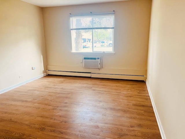 empty room featuring light wood-style floors, a baseboard radiator, a wall unit AC, and baseboards