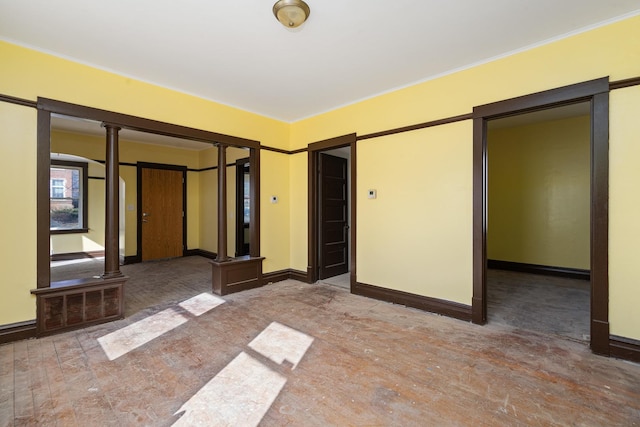 unfurnished room with baseboards, visible vents, and ornate columns