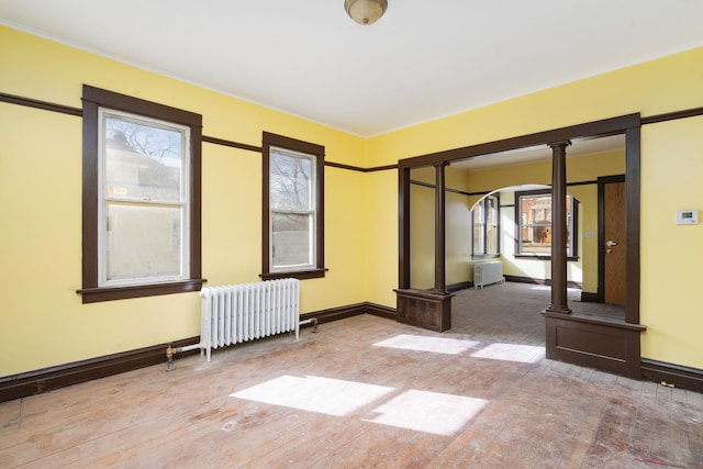 spare room with radiator, hardwood / wood-style flooring, and baseboards