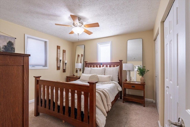 bedroom featuring ceiling fan, baseboards, a textured ceiling, and light colored carpet