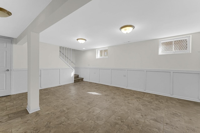 below grade area featuring wainscoting, visible vents, a decorative wall, and stairway