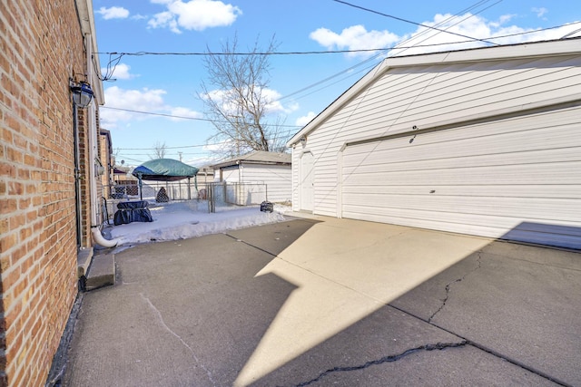 view of patio with a garage, an outbuilding, and fence