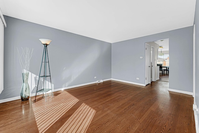 spare room featuring dark wood-style floors and baseboards