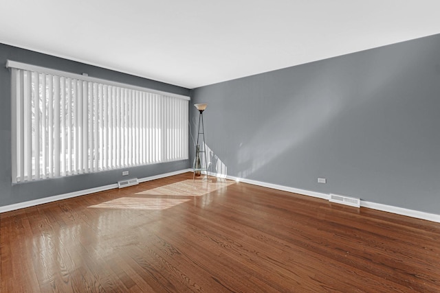 empty room featuring visible vents, baseboards, and wood finished floors