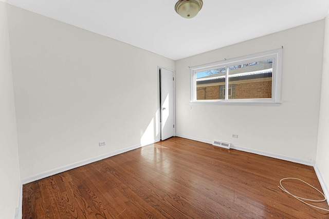 unfurnished room with visible vents, baseboards, and wood finished floors