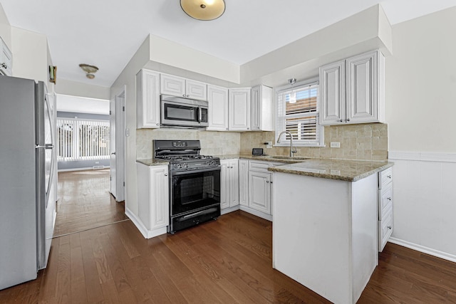 kitchen with stainless steel appliances, white cabinets, a sink, and light stone countertops