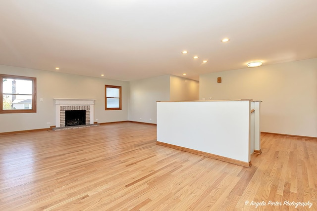 unfurnished living room featuring baseboards, a fireplace, light wood-style flooring, and recessed lighting