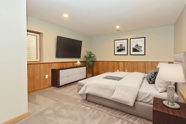 bedroom with light carpet, recessed lighting, wainscoting, and wooden walls