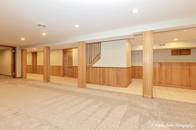 finished below grade area with a wainscoted wall, light carpet, and wooden walls