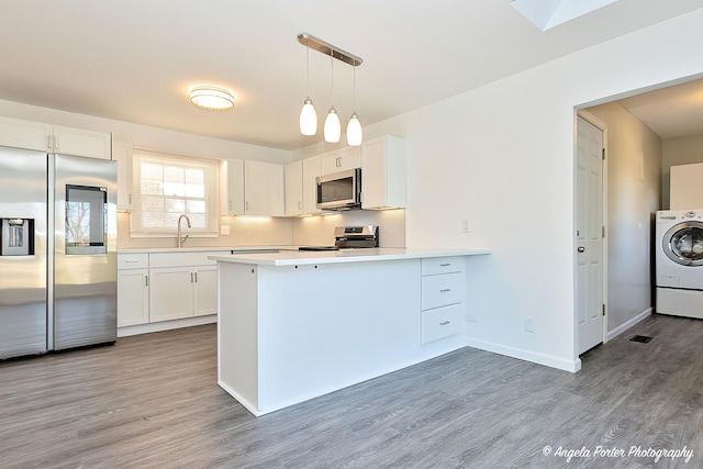 kitchen with stainless steel appliances, a peninsula, light countertops, and white cabinetry