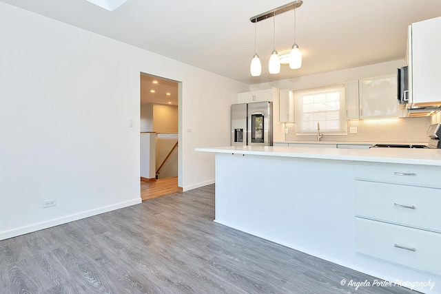 kitchen featuring pendant lighting, light countertops, stainless steel fridge, and white cabinets