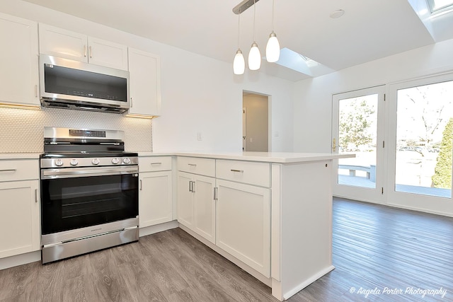 kitchen featuring a peninsula, appliances with stainless steel finishes, white cabinets, and light countertops