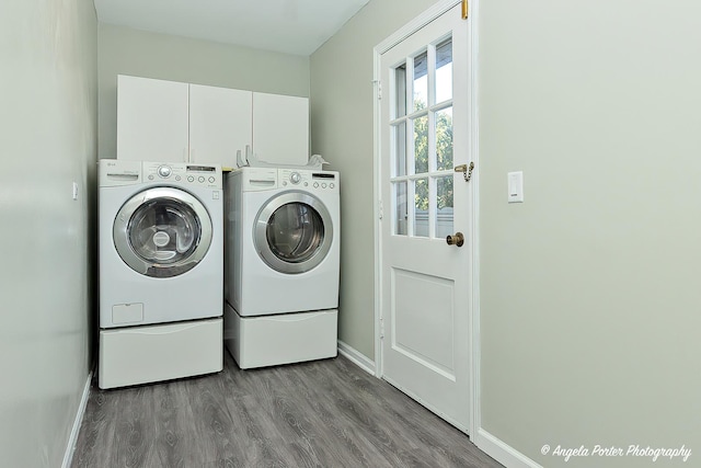 clothes washing area featuring cabinet space, independent washer and dryer, baseboards, and wood finished floors