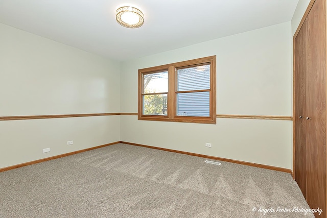 empty room featuring carpet, visible vents, and baseboards