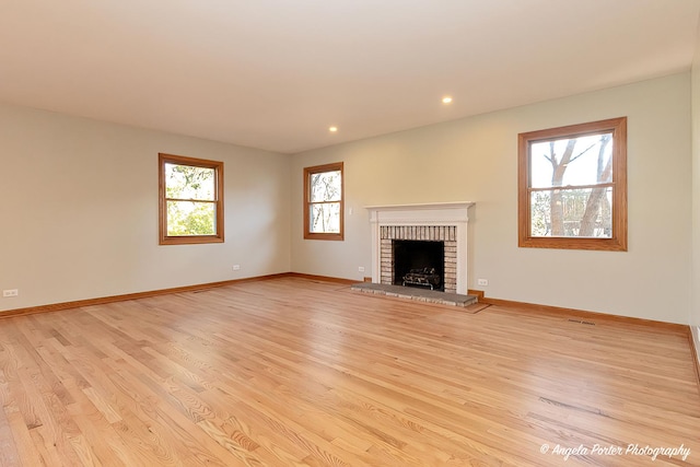 unfurnished living room with light wood-style floors, a fireplace, and baseboards