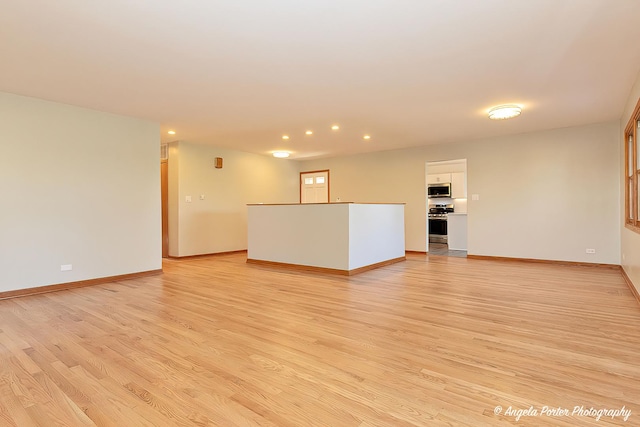 unfurnished living room with recessed lighting, light wood-style flooring, and baseboards