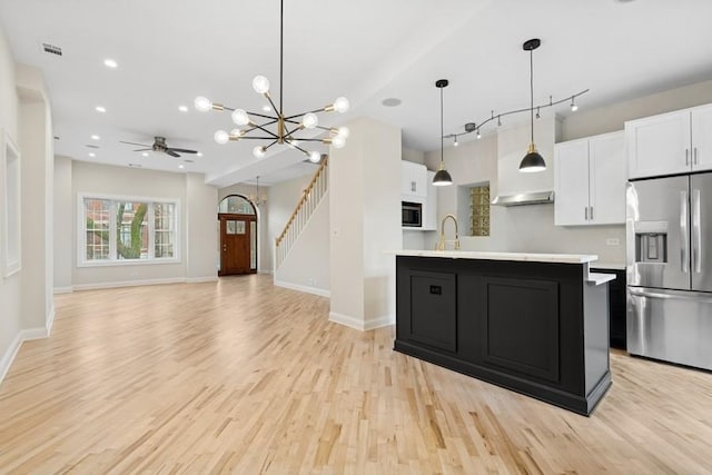 kitchen with white cabinets, light wood finished floors, stainless steel fridge, and light countertops