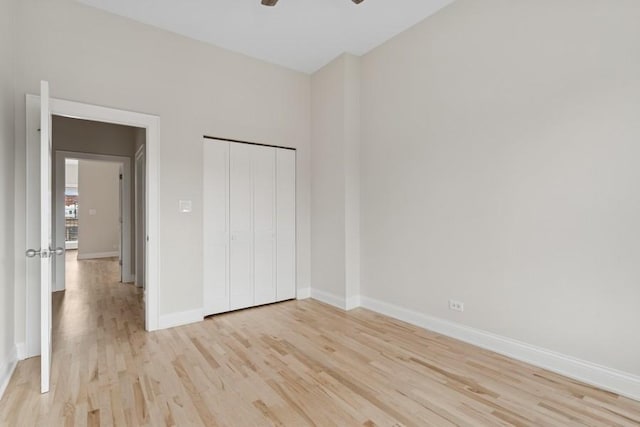 unfurnished bedroom featuring ceiling fan, a closet, light wood-type flooring, and baseboards