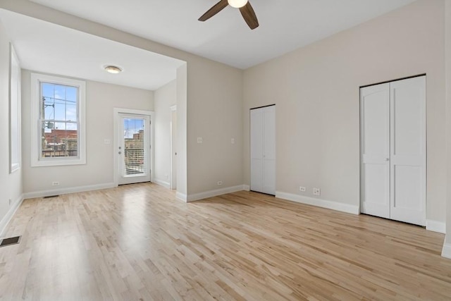 unfurnished bedroom featuring access to exterior, visible vents, light wood finished floors, and two closets