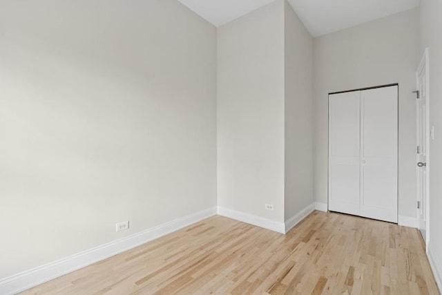 unfurnished bedroom featuring light wood finished floors, baseboards, and a closet