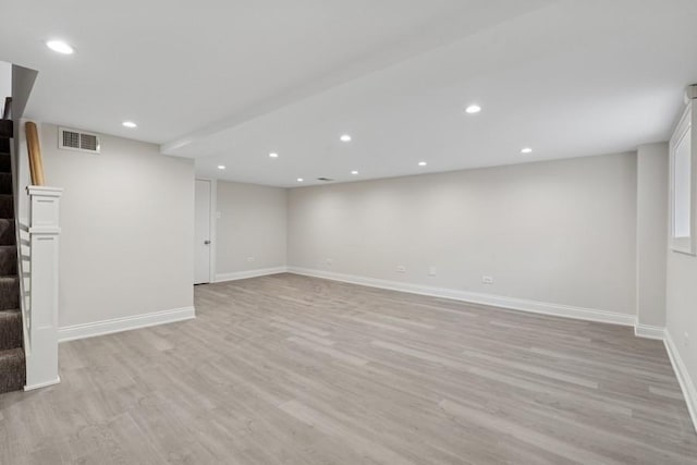 finished basement with baseboards, visible vents, stairs, light wood-type flooring, and recessed lighting