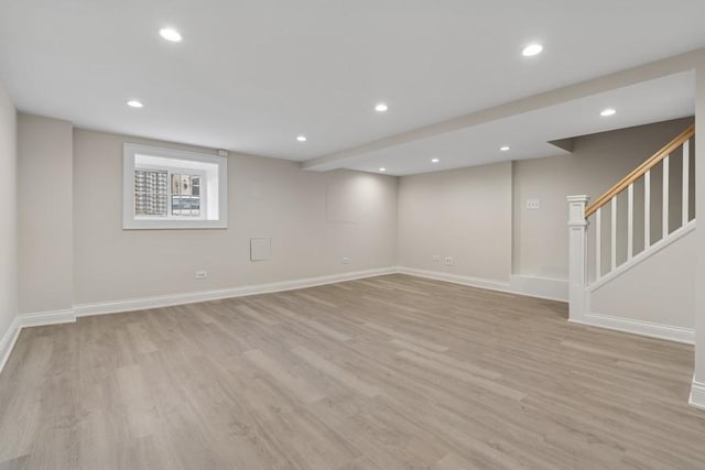 below grade area with recessed lighting, light wood-style flooring, baseboards, and stairs