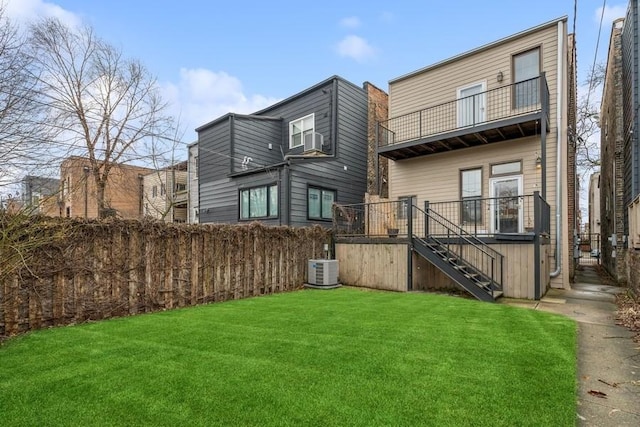 back of property with central AC unit, a balcony, stairway, and a lawn