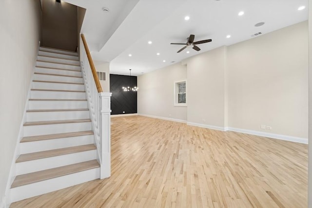 unfurnished living room featuring baseboards, recessed lighting, stairs, and light wood-style floors