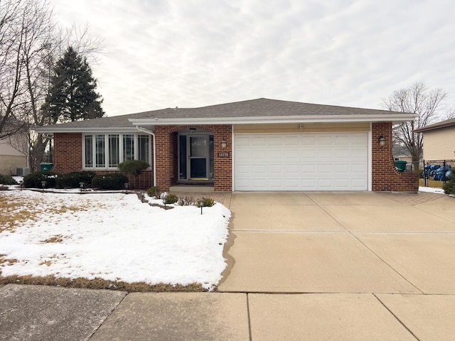 single story home featuring driveway, roof with shingles, a garage, and brick siding