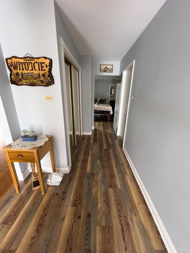 hallway with dark wood-style flooring and baseboards