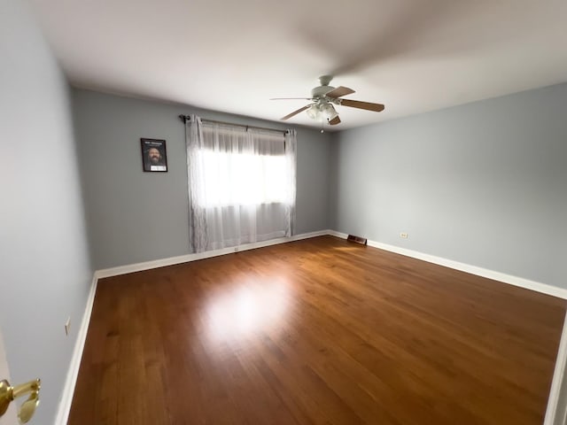 empty room featuring ceiling fan, baseboards, and wood finished floors