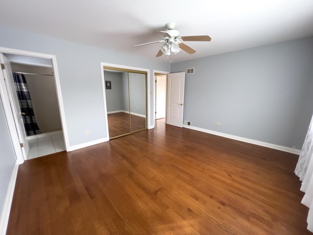 unfurnished bedroom featuring dark wood-style floors, baseboards, visible vents, and ceiling fan