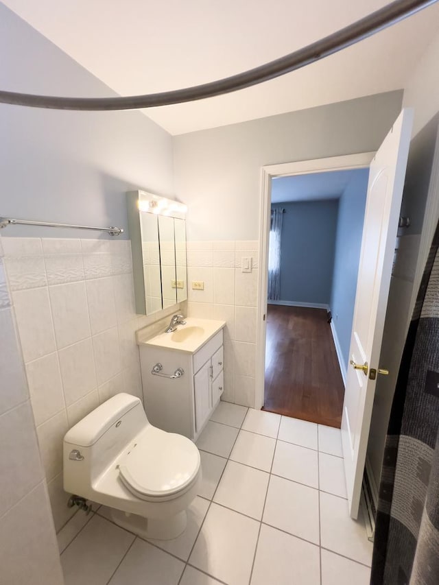 bathroom with toilet, tile patterned flooring, vanity, and tile walls