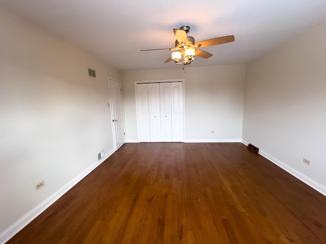 unfurnished bedroom with dark wood-style flooring, a closet, visible vents, and baseboards