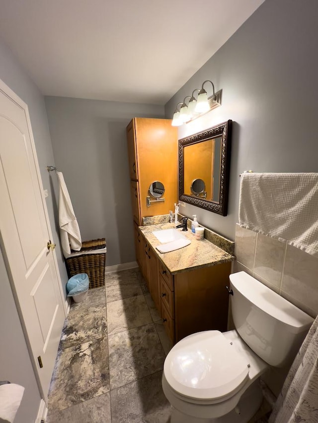 half bathroom featuring vanity, toilet, and baseboards