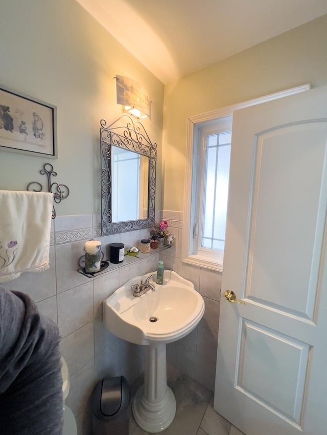 bathroom with a sink, a wainscoted wall, and tile walls