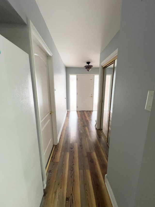 hallway with dark wood finished floors and baseboards