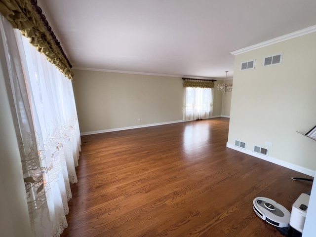 empty room with dark wood-type flooring, visible vents, and ornamental molding