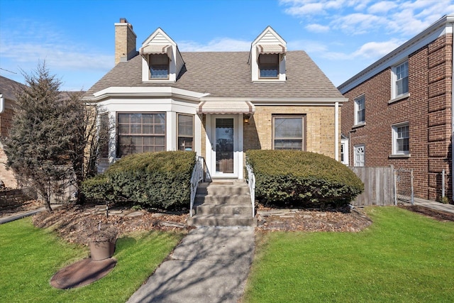 new england style home with a shingled roof, a chimney, a front yard, and fence