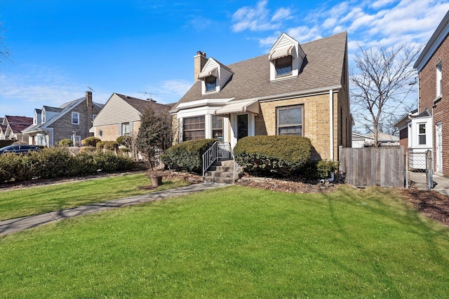 new england style home featuring brick siding, fence, a chimney, and a front lawn