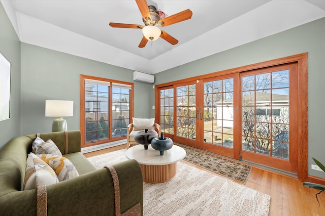 sitting room featuring wood finished floors, a ceiling fan, an AC wall unit, french doors, and a tray ceiling