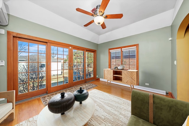 sitting room with baseboards, arched walkways, wood finished floors, and an AC wall unit