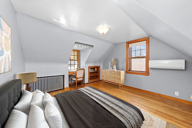 bedroom with multiple windows, radiator heating unit, a wall mounted air conditioner, and wood finished floors