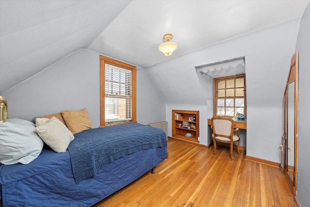 bedroom with lofted ceiling, light wood finished floors, multiple windows, and baseboards