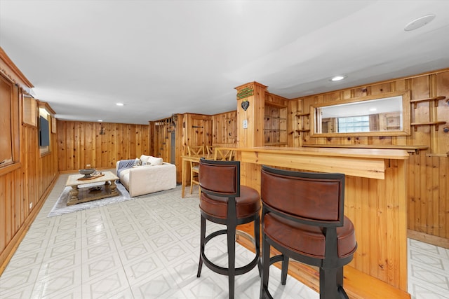 kitchen featuring light floors, recessed lighting, wood walls, and a kitchen breakfast bar