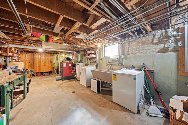 basement with a heating unit, refrigerator, washing machine and clothes dryer, water heater, and a sink