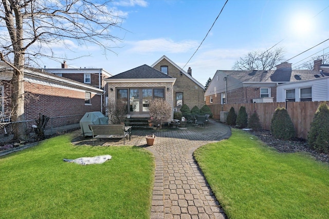 back of house with brick siding, a lawn, entry steps, a patio area, and fence