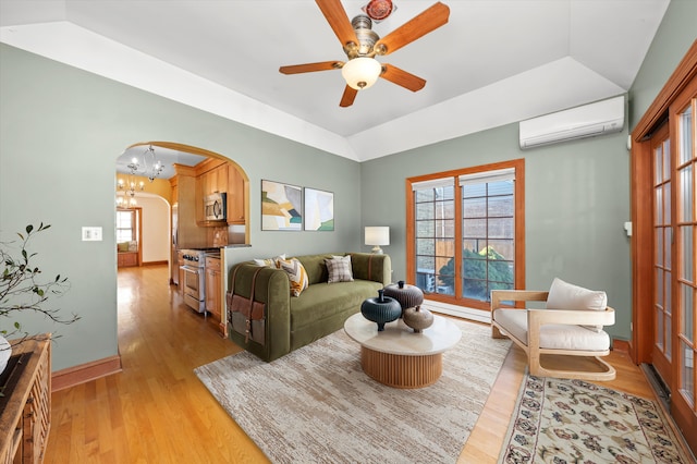 living room featuring arched walkways, lofted ceiling, a ceiling fan, a wall mounted AC, and light wood-type flooring